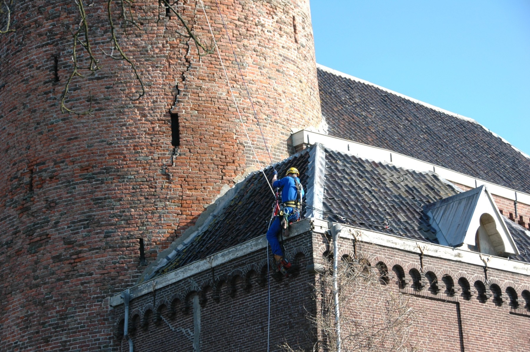 Een restaurateur werkt aan touwen naast de donjon en het dak