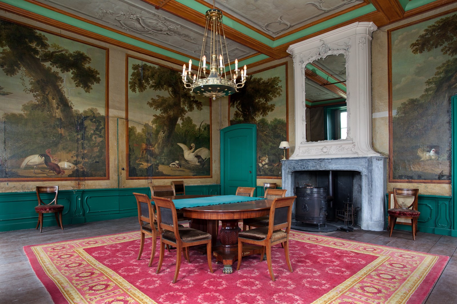 De eetkamer van Kasteel Loenersloot met tafel, stoelen, groen geschilderd houtwerk en beschilderde wanden